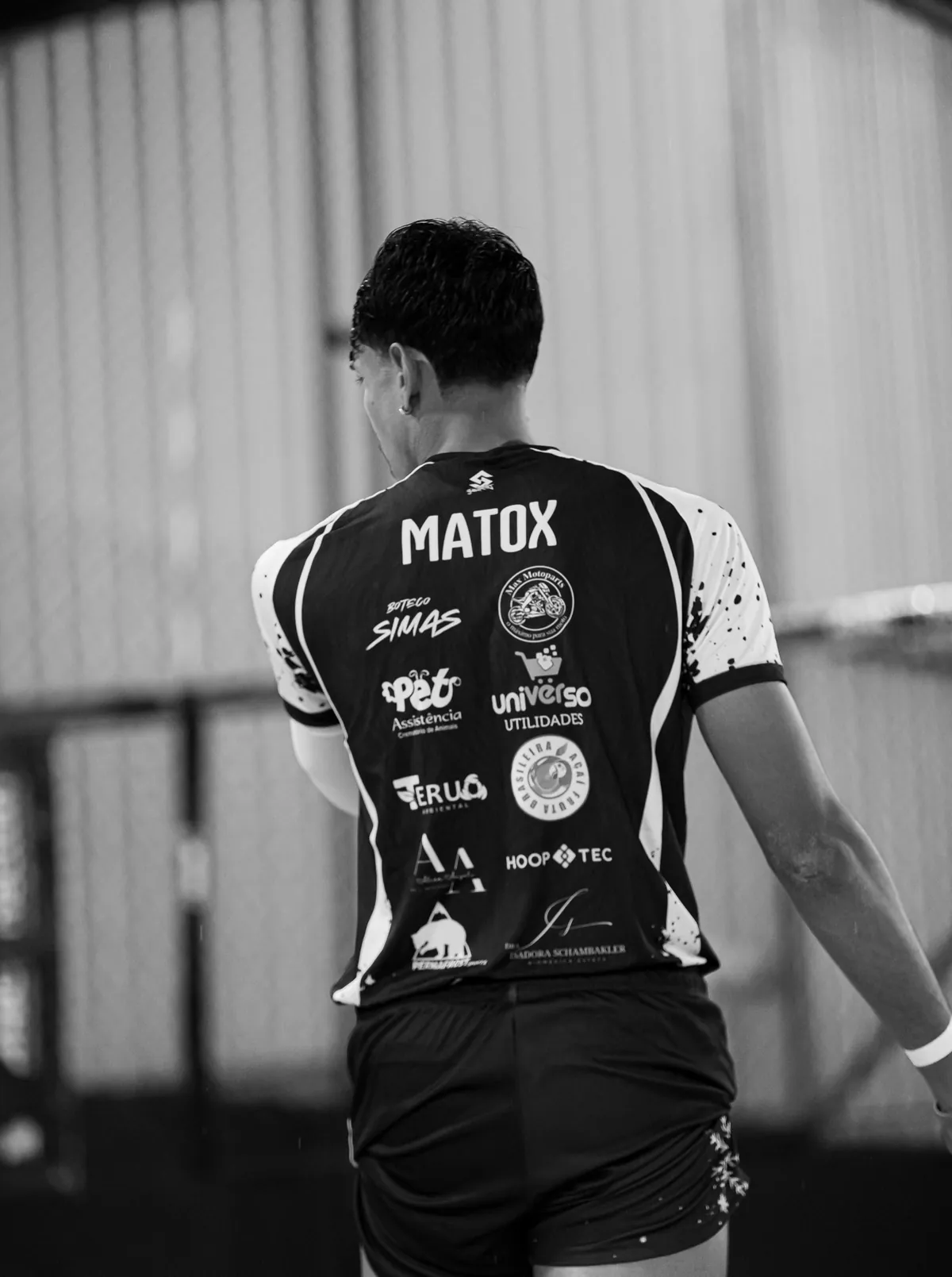 Foto em preto e branco de Matox de costas, com o nome na camisa